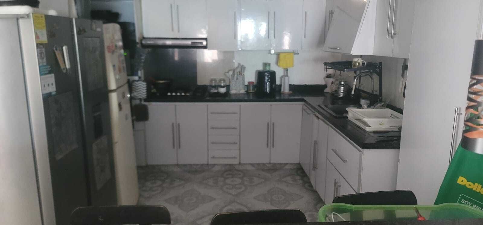 A compact kitchen with white cabinets, a black countertop, and a patterned floor.