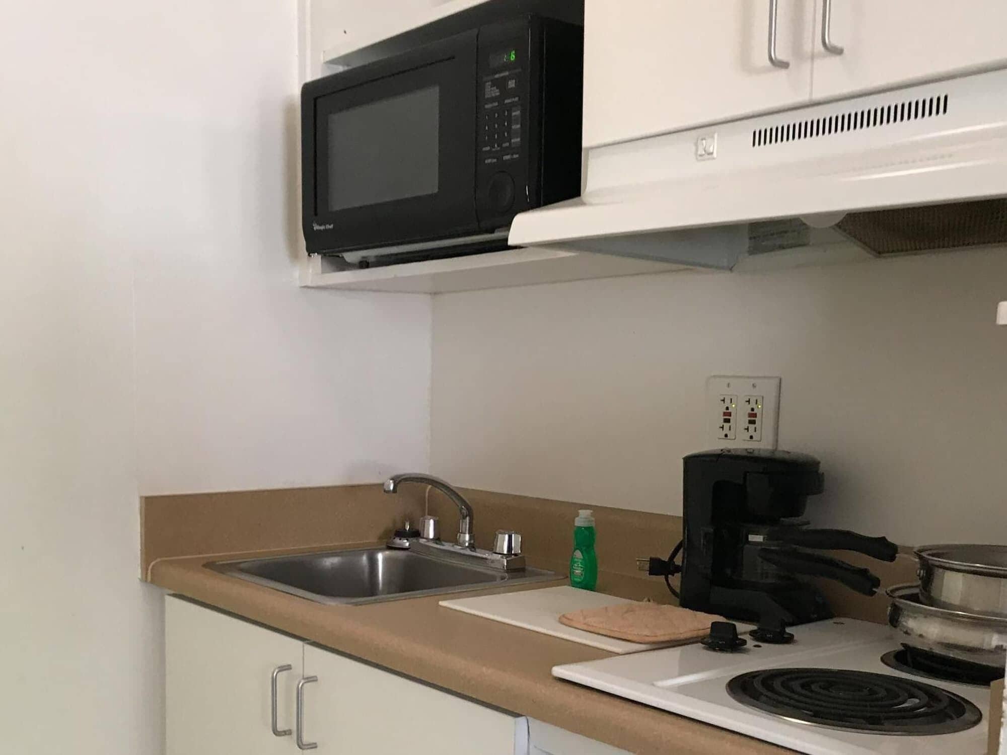 A kitchen with a microwave, sink, coffee maker, and stove.