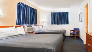 Habitació d'hotel amb dos llits, una cadira, un armari i una finestra amb cortines.