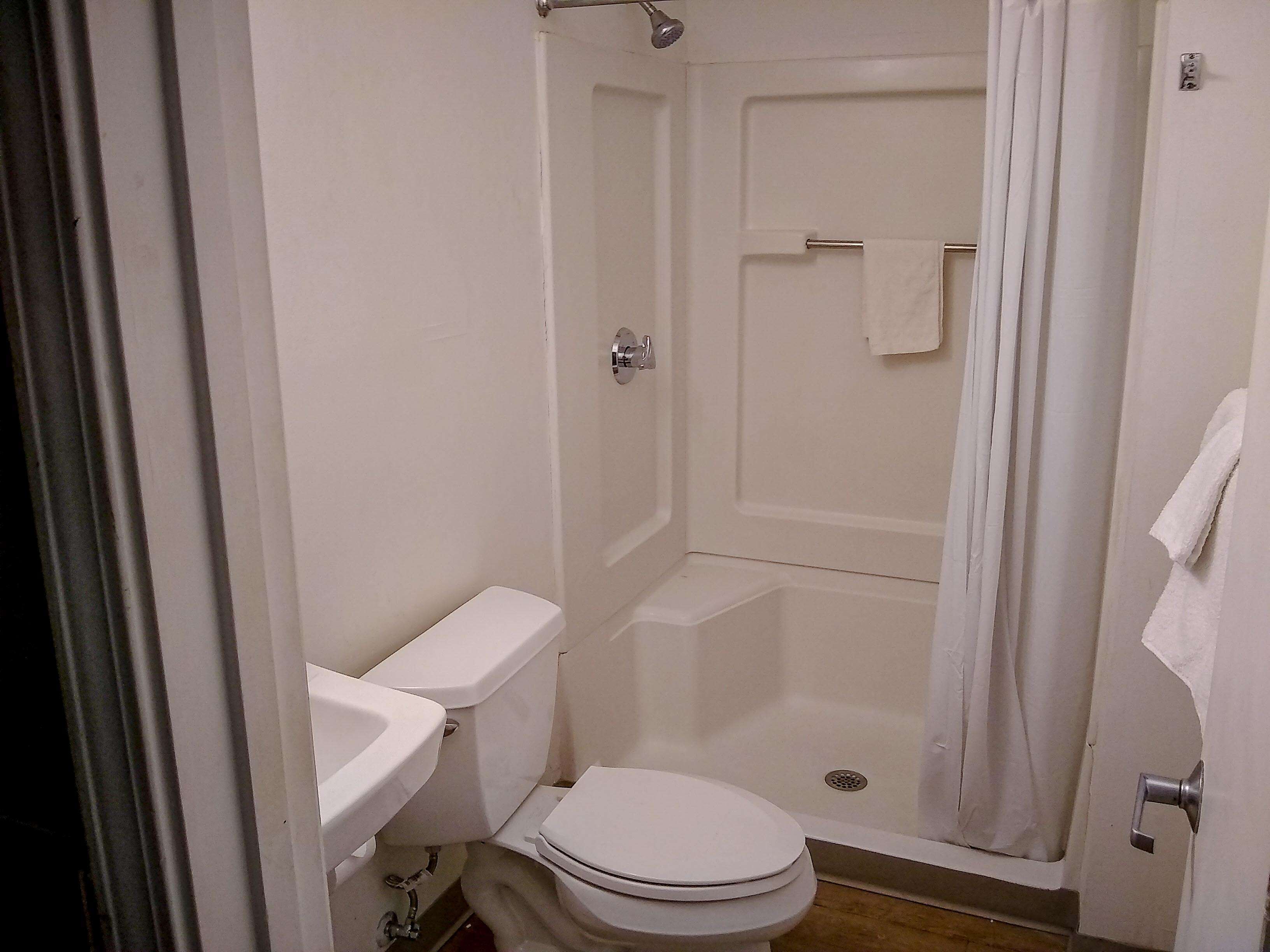 A small, compact bathroom with a toilet, sink, and shower.