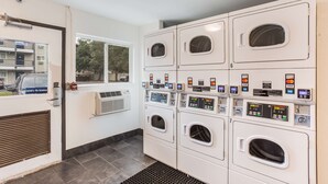 Un lavadero con varias máquinas, una ventana y una puerta.