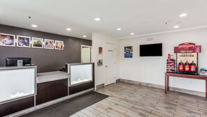 Zona de recepción con mostrador, estación de café y televisor en la pared.