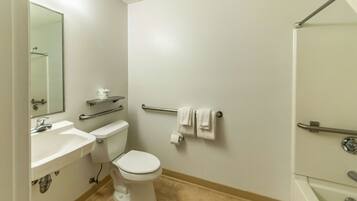 A bathroom with a toilet, sink, mirror, and towel rack.