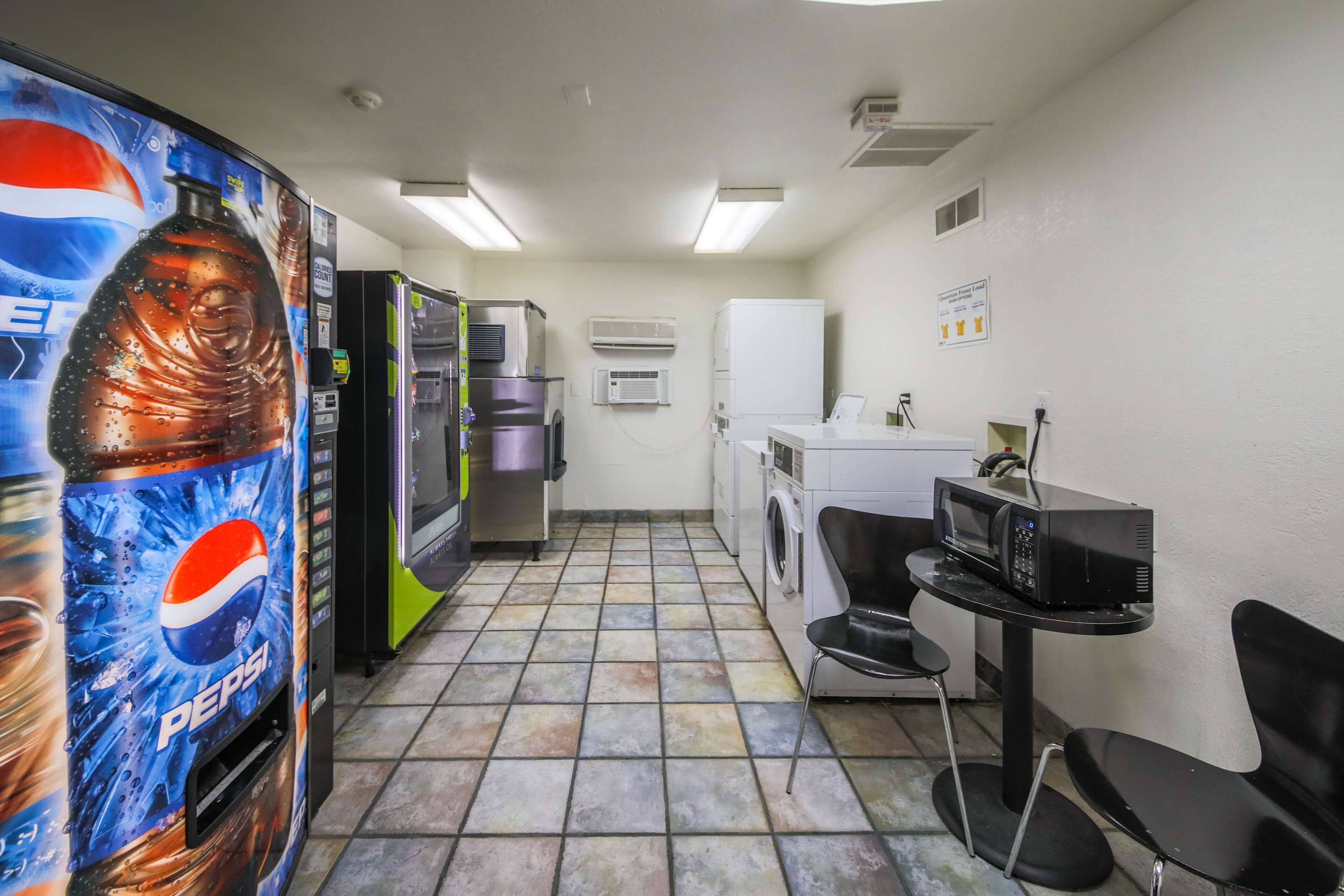 A compact kitchen area with a washing machine, a microwave, and a refrigerator.