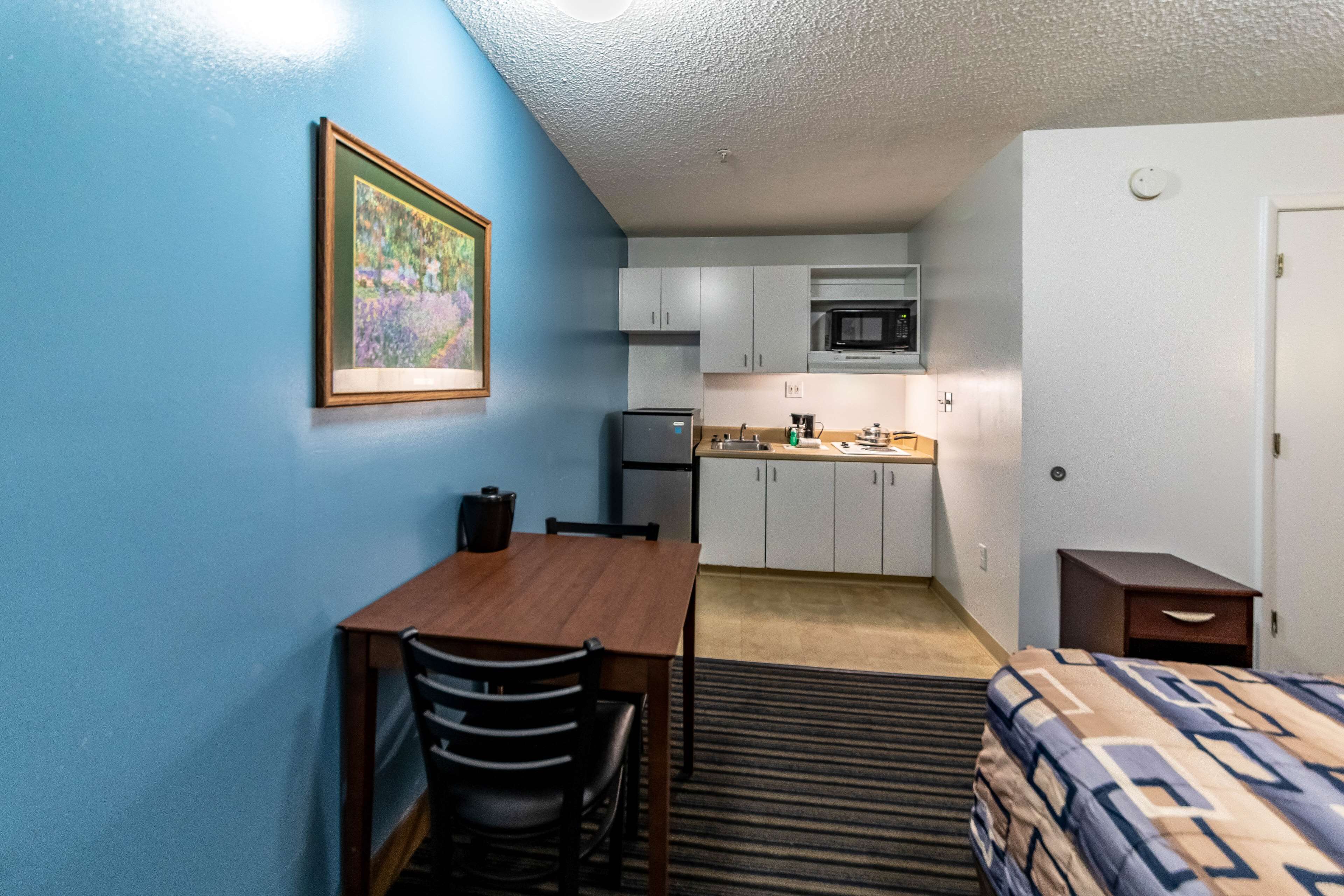 A compact room with a kitchenette, a dining area, and a bed.