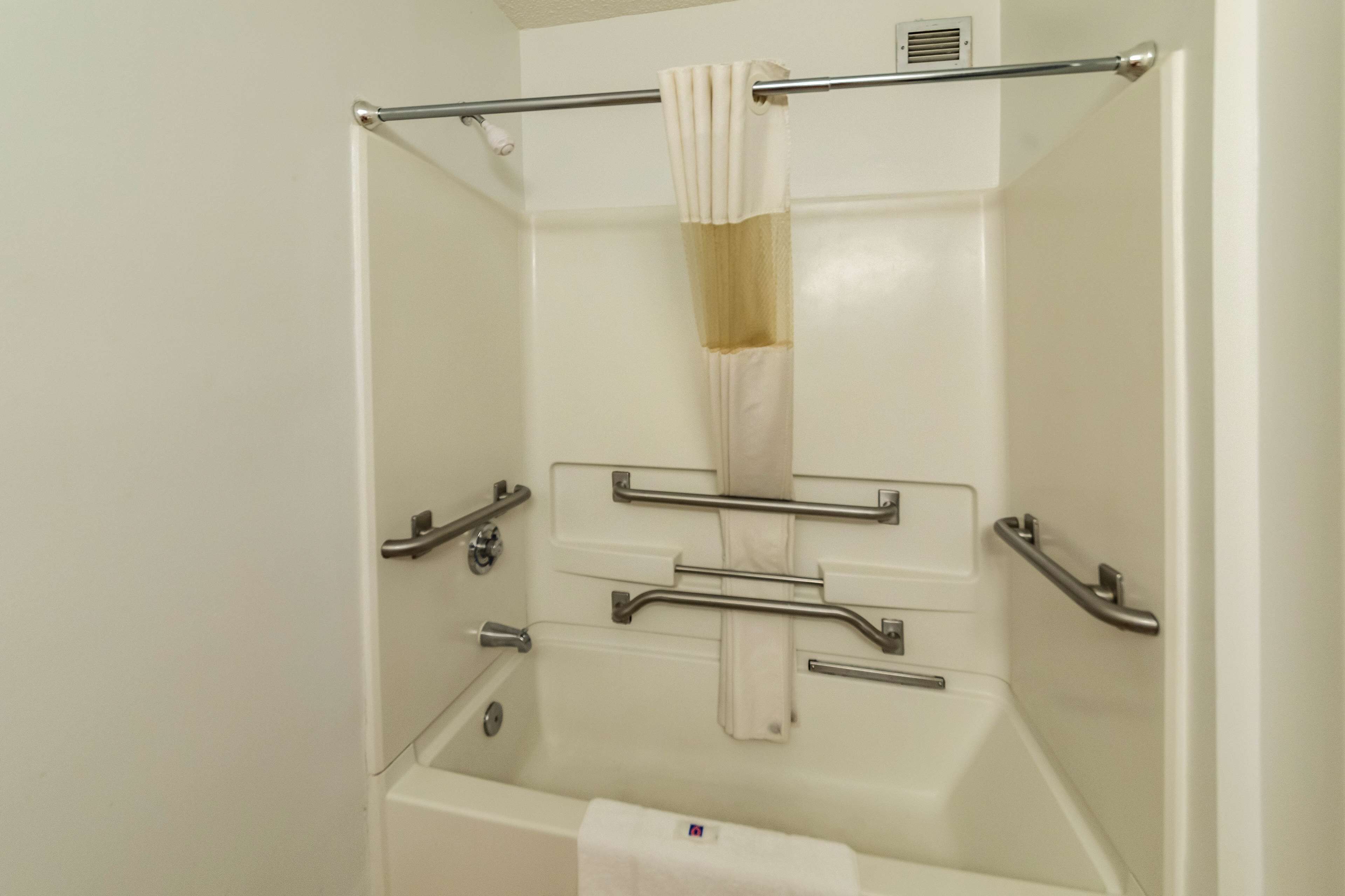 Une salle de bain avec une baignoire blanche, des barres d’appui et un porte-serviettes.