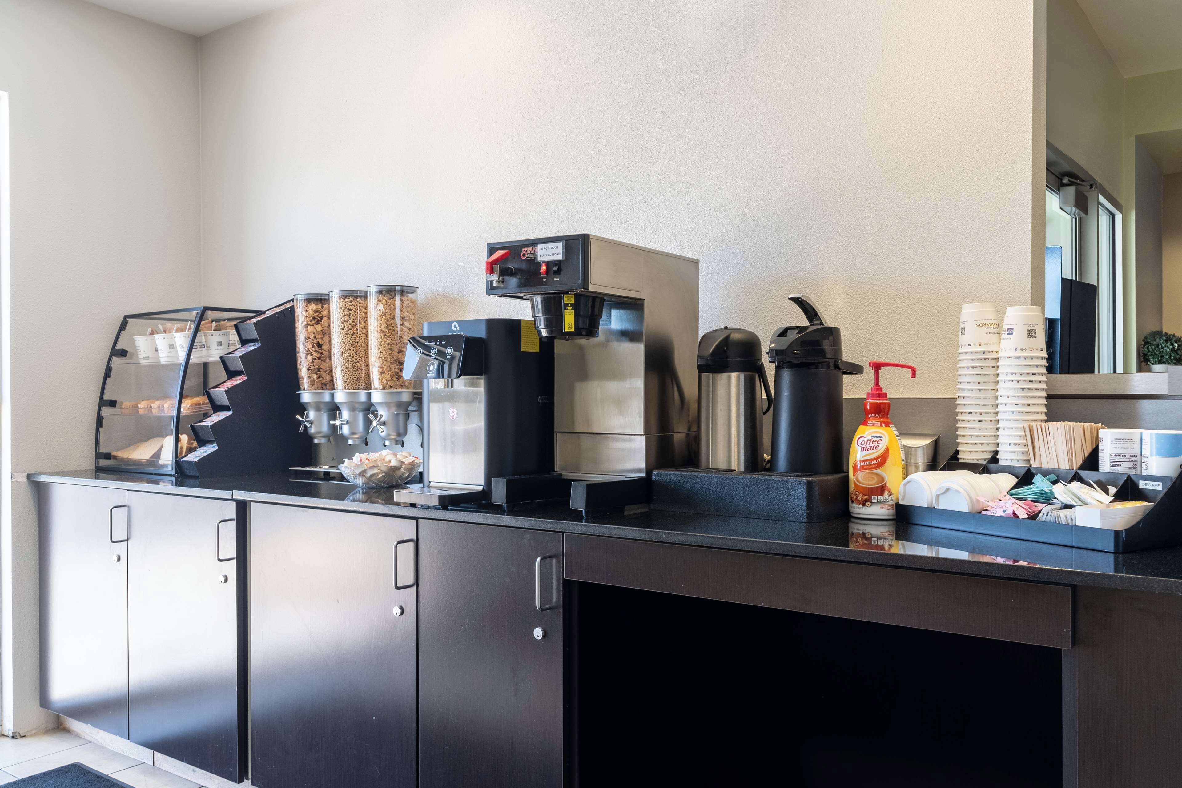 Un espace dédié au café, équipé d’une machine à café, de distributeurs de condiments et d’un assortiment de capsules de café.
