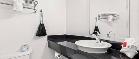 A modern bathroom with a black countertop sink, a white toilet, and a towel rack above the toilet.