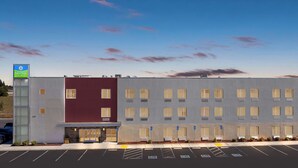 A modern hotel building with a red and grey facade, a parking lot with marked handicapped spaces, and a SureStay sign. - SureStay by Best Western Livingston Merced County (Livingston)