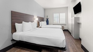 A hotel room with two beds, a flat-screen TV mounted on the wall, a window with blinds, and a small table with a lamp. - SureStay by Best Western Livingston Merced County (Livingston)