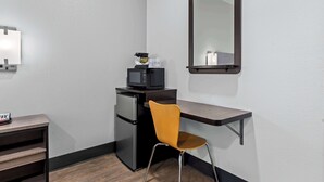 A compact room with a kitchenette, a microwave, a refrigerator, a small table with a phone, a chair, and a mirror on the wall. - SureStay by Best Western Livingston Merced County (Livingston)