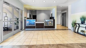 A reception area with a check-in counter, glass doors, potted plants, and a tiled floor. - SureStay by Best Western Livingston Merced County (Livingston)