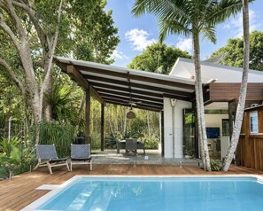 A poolside area with a covered patio, lounge chairs, and a dining table. - Luxe Beachfront Haven w/heated pool. Pet-Friendly (Broken Head)