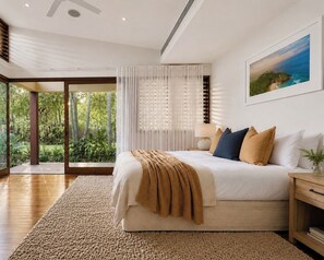 A bedroom with a large bed, a view of greenery through a sliding door, and a painting on the wall. - Luxe Beachfront Haven w/heated pool. Pet-Friendly (Broken Head)