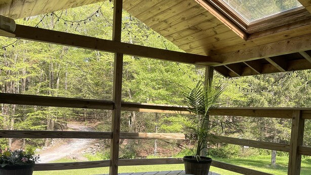 Ett bubbelbad under en träveranda med utsikt över ett skogsområde.