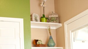 Un coin de pièce avec une porte blanche, un mur vert et une étagère ornée d’objets décoratifs.