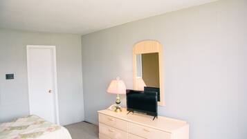 A bedroom with a bed, dresser, mirror, and lamp.