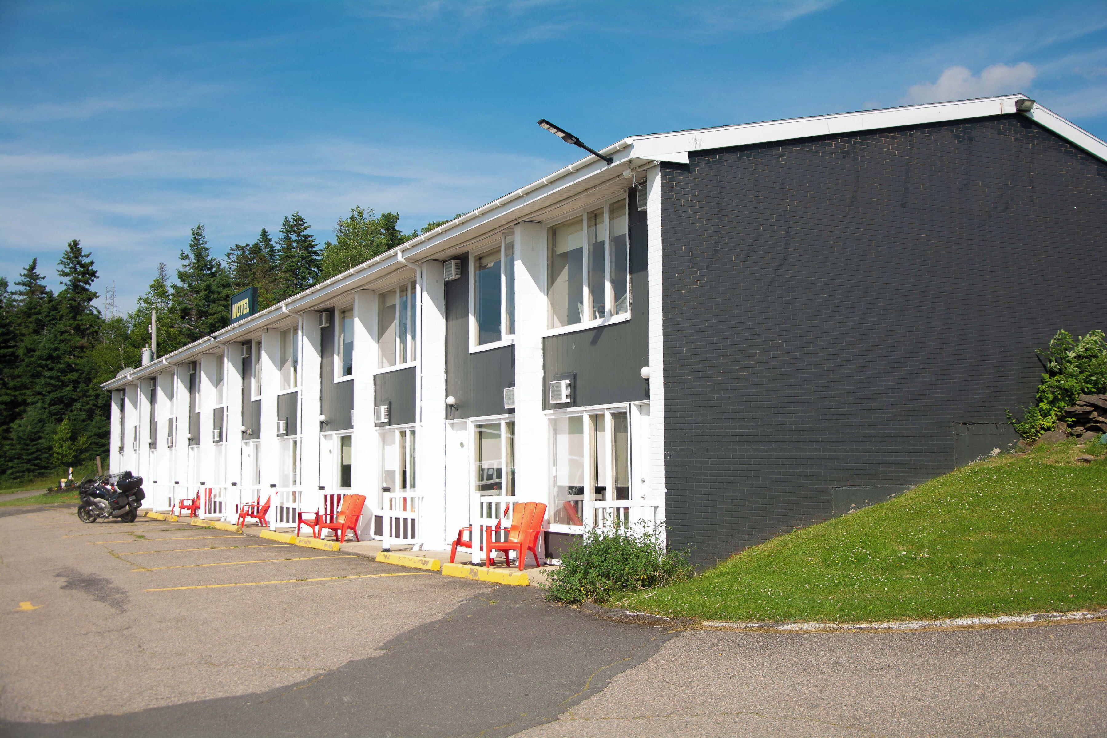 Un motel con varias habitaciones, un área de estacionamiento y una motocicleta estacionada afuera.