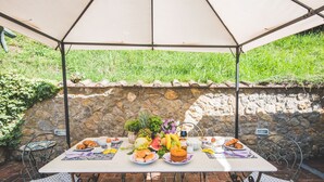 An outdoor dining setup with a table, chairs, and a stone wall backdrop. - Beautiful house with swimming pool surrounded by greenery, modern, luxury finishes (Camaiore)