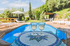 A poolside area with a mosaic table, lounge chairs, and a pergola. - Beautiful house with swimming pool surrounded by greenery, modern, luxury finishes (Camaiore)