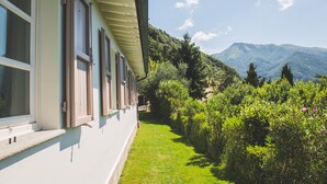 A building with a balcony overlooking a lush garden and a mountain range. - Beautiful house with swimming pool surrounded by greenery, modern, luxury finishes (Camaiore)