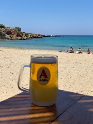 A beach scene with a clear sky, a sandy shore, and a glass mug with a logo.