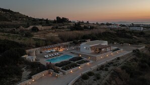 A resort with a swimming pool, lounge chairs, and a covered patio area. - H2O Private Villa Paros, infinity swimming pool, sea view lounge area, bbq & Bar (Koukoulavmes)
