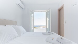 A hotel room with a bed, a view through an open door, and a window. - H2O Private Villa Paros, infinity swimming pool, sea view lounge area, bbq & Bar (Koukoulavmes)