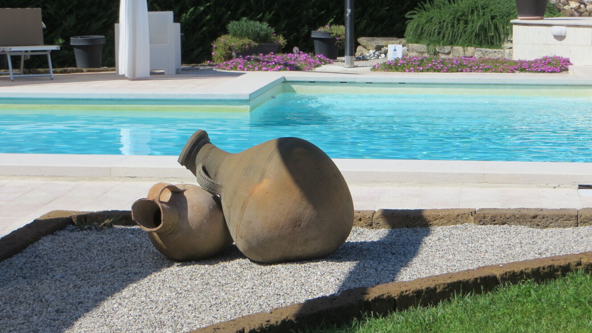 Un espace piscine agrémenté de deux grands pots en céramique placés sur un lit de gravier.