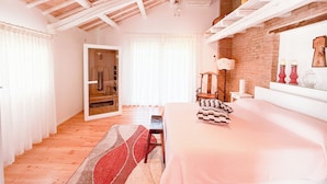A bedroom with a large bed, a wooden chair, a small table, and a mirror on the wall.