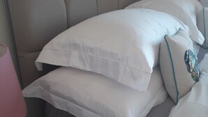 Een bed met hoofdbord, kussens en een nachtkastje met een lamp.
