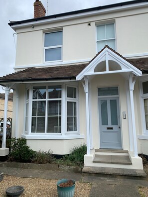 A two-story house with a white facade, a front porch, and a grey door.