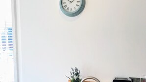 Una cocina moderna con encimera de madera, pileta de acero inoxidable, un reloj en la pared y una pequeña planta en maceta.