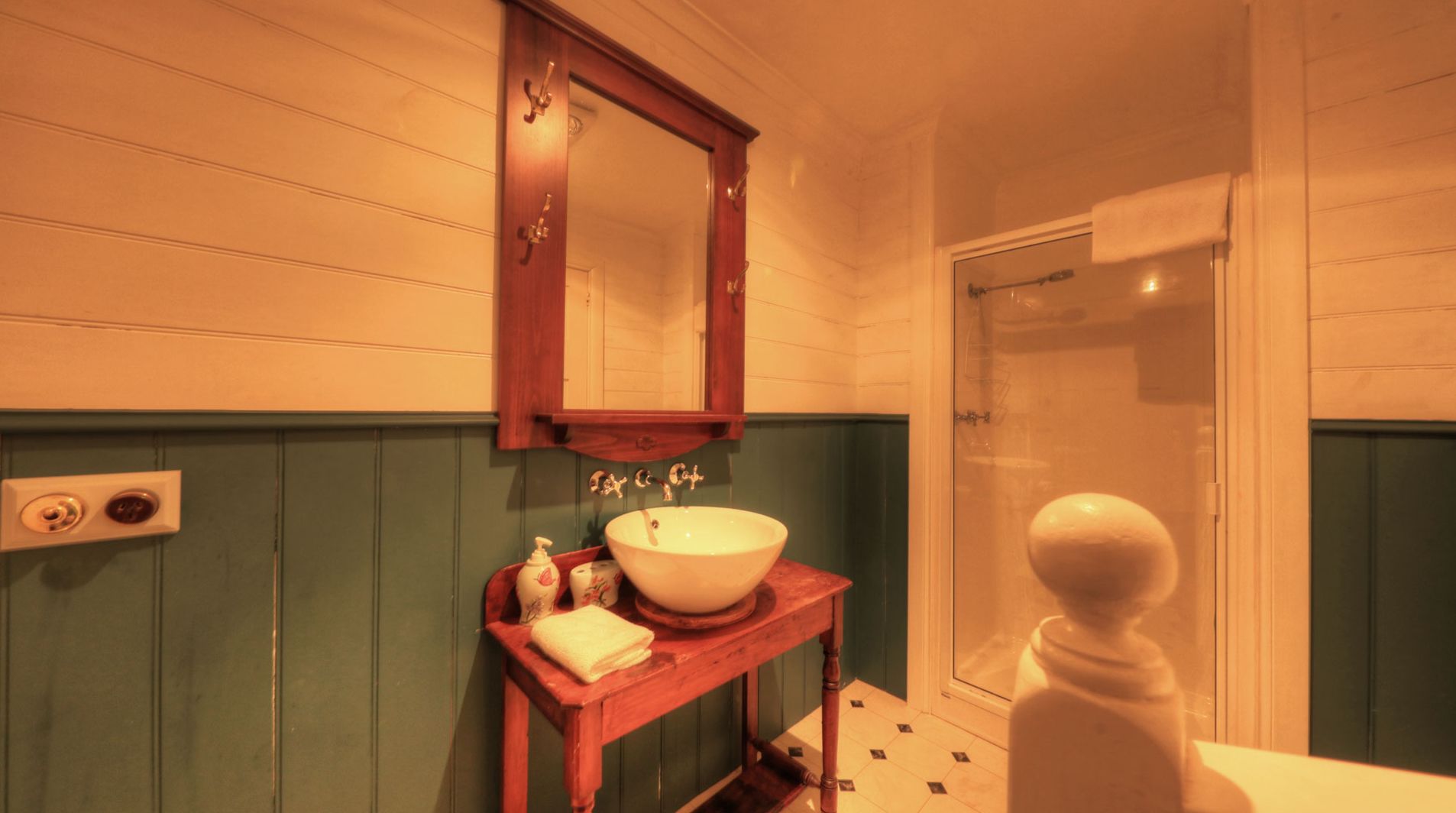 A bathroom with a wooden vanity, a white sink, and a mirror above it.