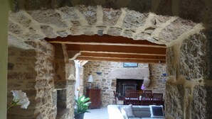 A stone-walled interior with a fireplace, a sofa, and a dining table. - CHARACTER HOUSE: 28° covered SWIMMING POOL, SPA, JACCUZZI  (Plourin)