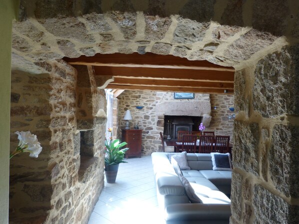 A stone-walled interior with a fireplace, a sofa, and a dining table.