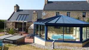 A glass conservatory with a pool, stone house, and outdoor seating area. - CHARACTER HOUSE: 28° covered SWIMMING POOL, SPA, JACCUZZI  (Plourin)