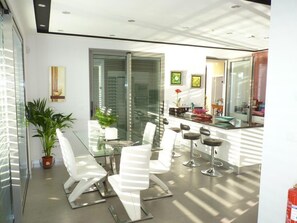 Enjoy dining in a contemporary space with a glass table, white chairs, and framed artwork.
