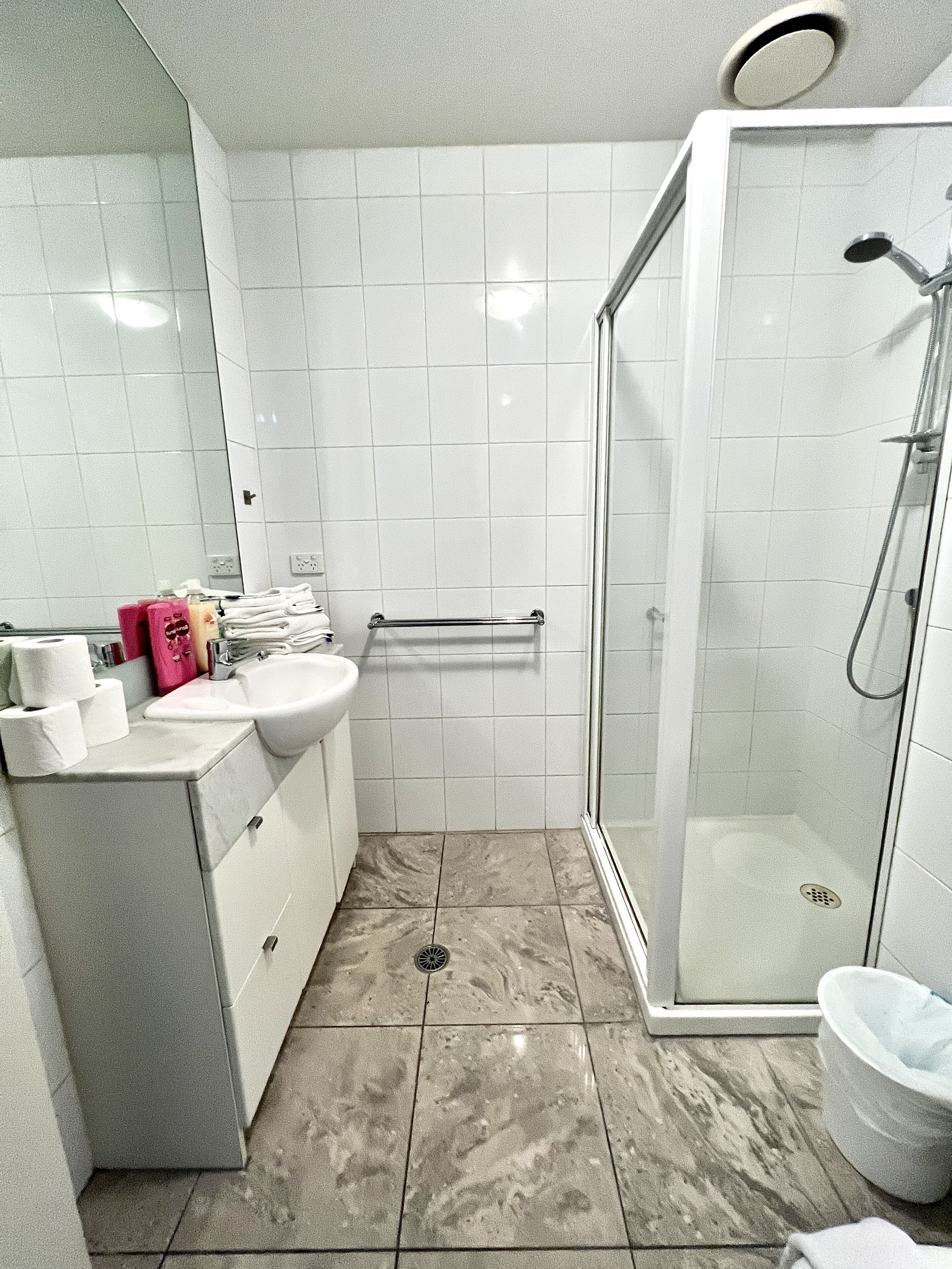 Une salle de bain avec une douche en verre, un lavabo et un meuble-lavabo avec des articles de toilette.