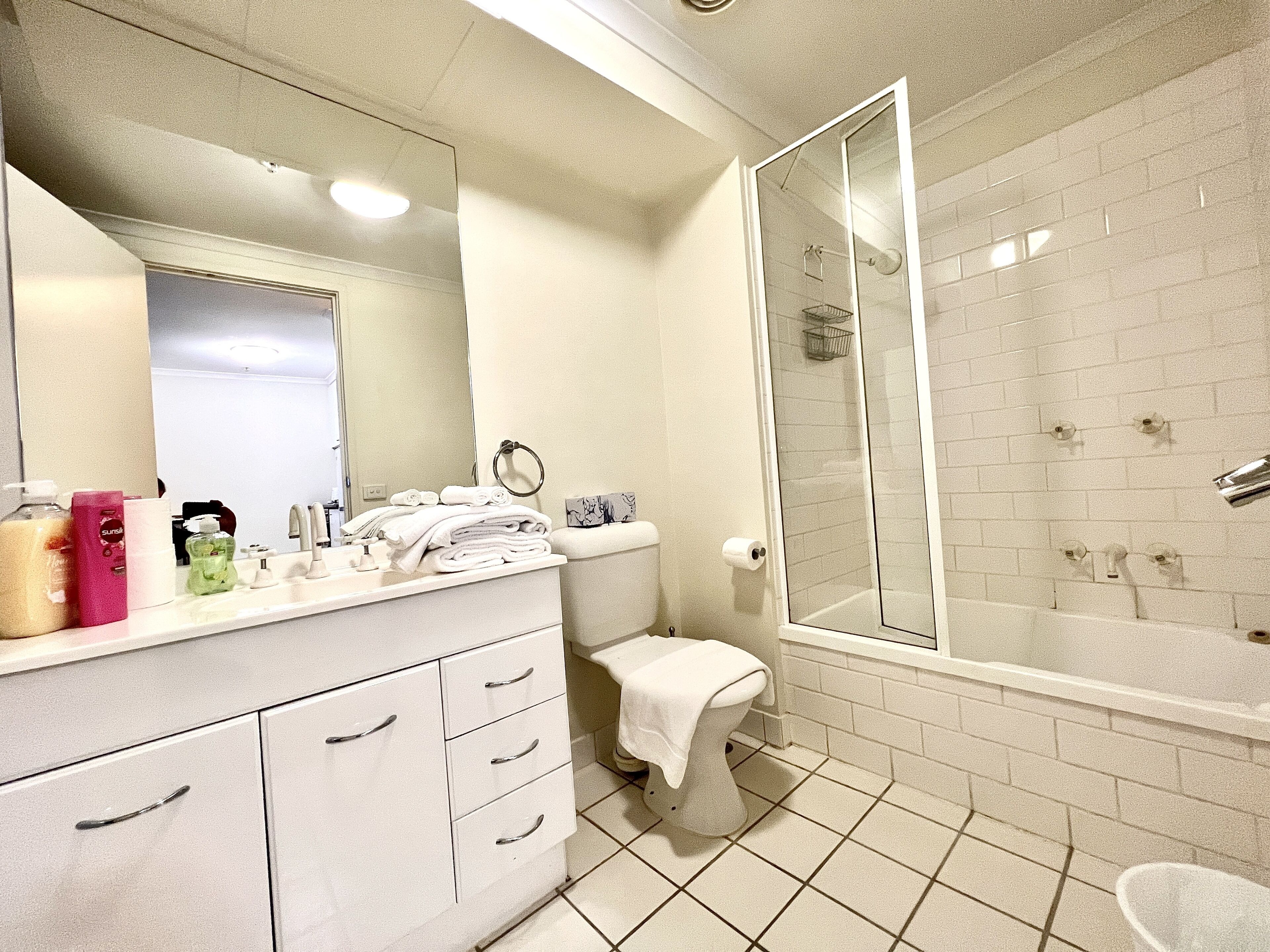 A modern bathroom with a white vanity, a glass shower enclosure, and a toilet.