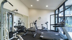 Un gimnasio con equipo cardiovascular, máquinas de pesas y un espejo.