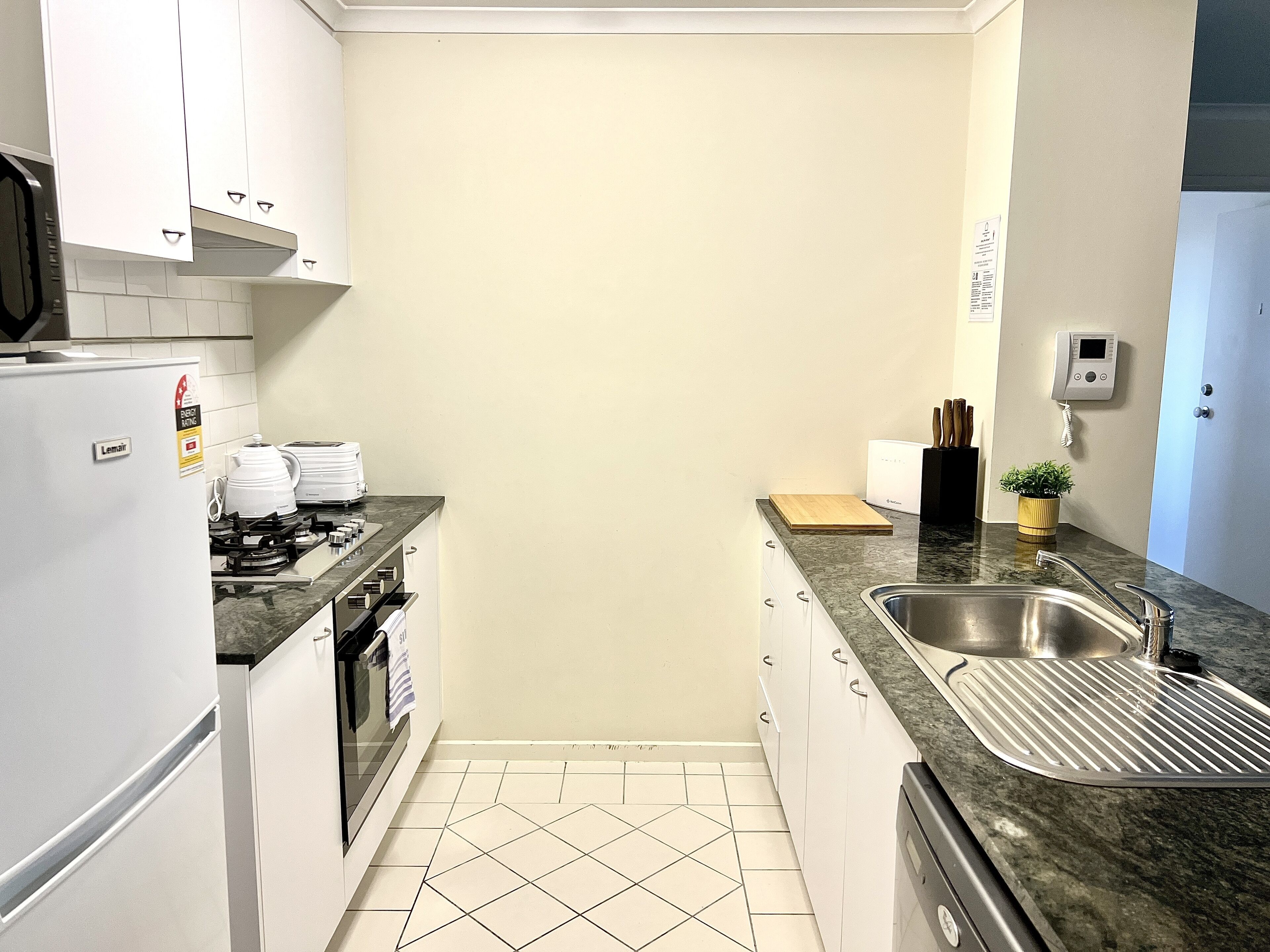 A compact kitchen with white cabinets, a gas stove, a sink, and a small countertop.