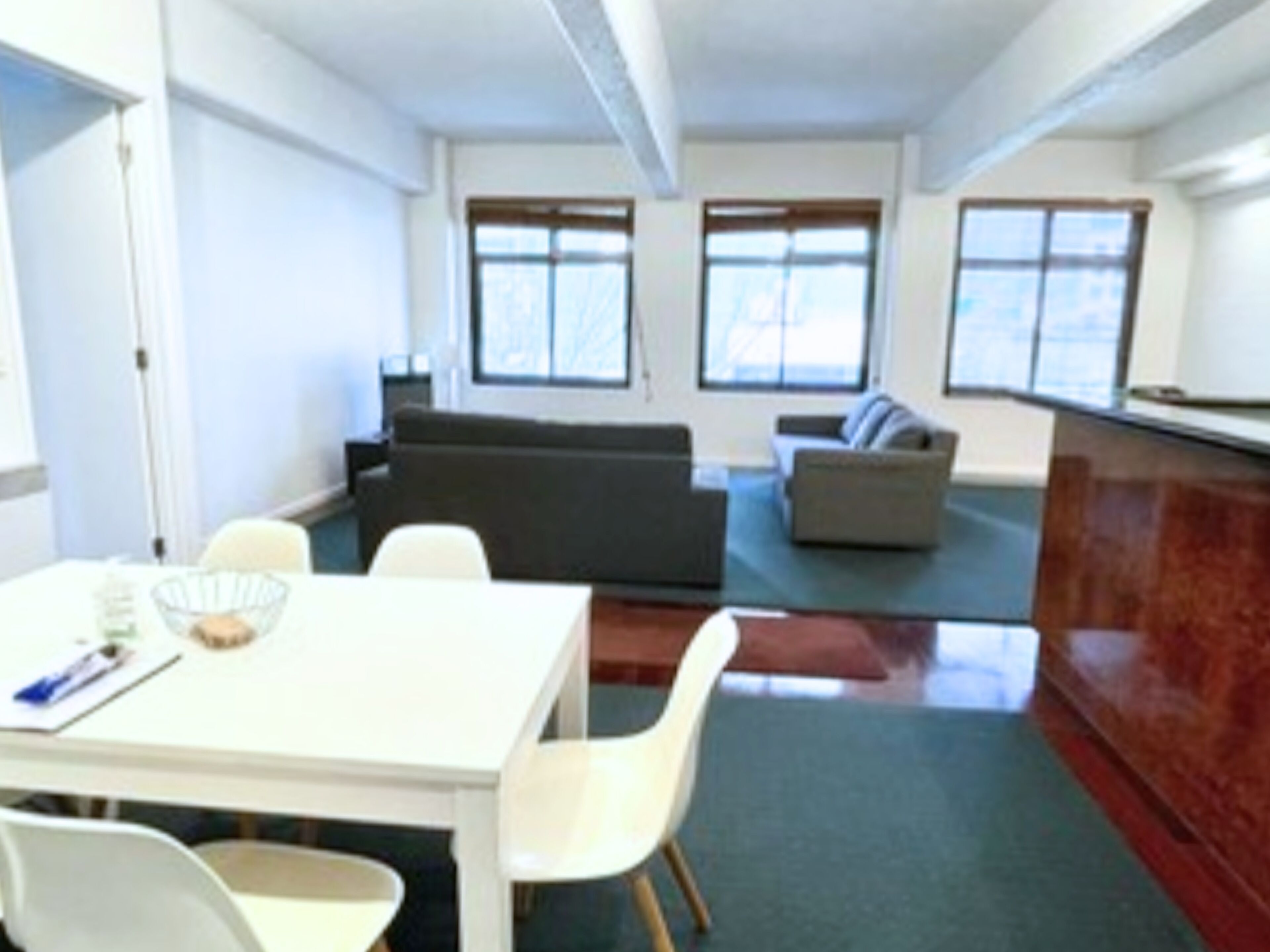 Una habitación moderna con una mesa de comedor, sillas, un sofá y una zona de cocina.