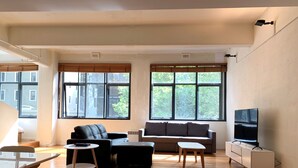Un salón amplio con sofá, reposapiés y televisor sobre un mueble.