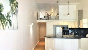 Una cocina moderna con armarios blancos, encimera negra y refrigerador de acero inoxidable.