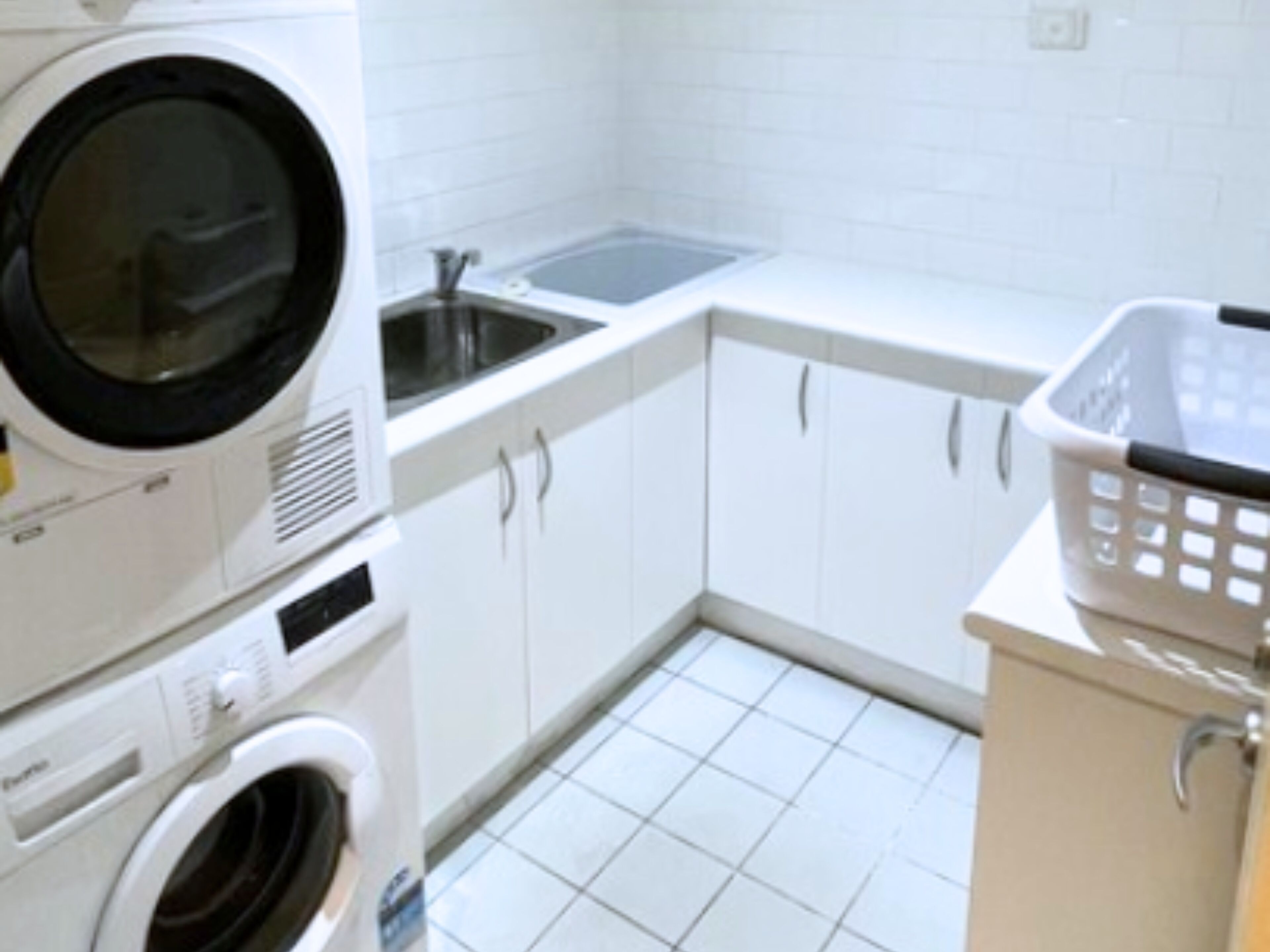 A compact laundry area with a washing machine, dryer, and a sink.