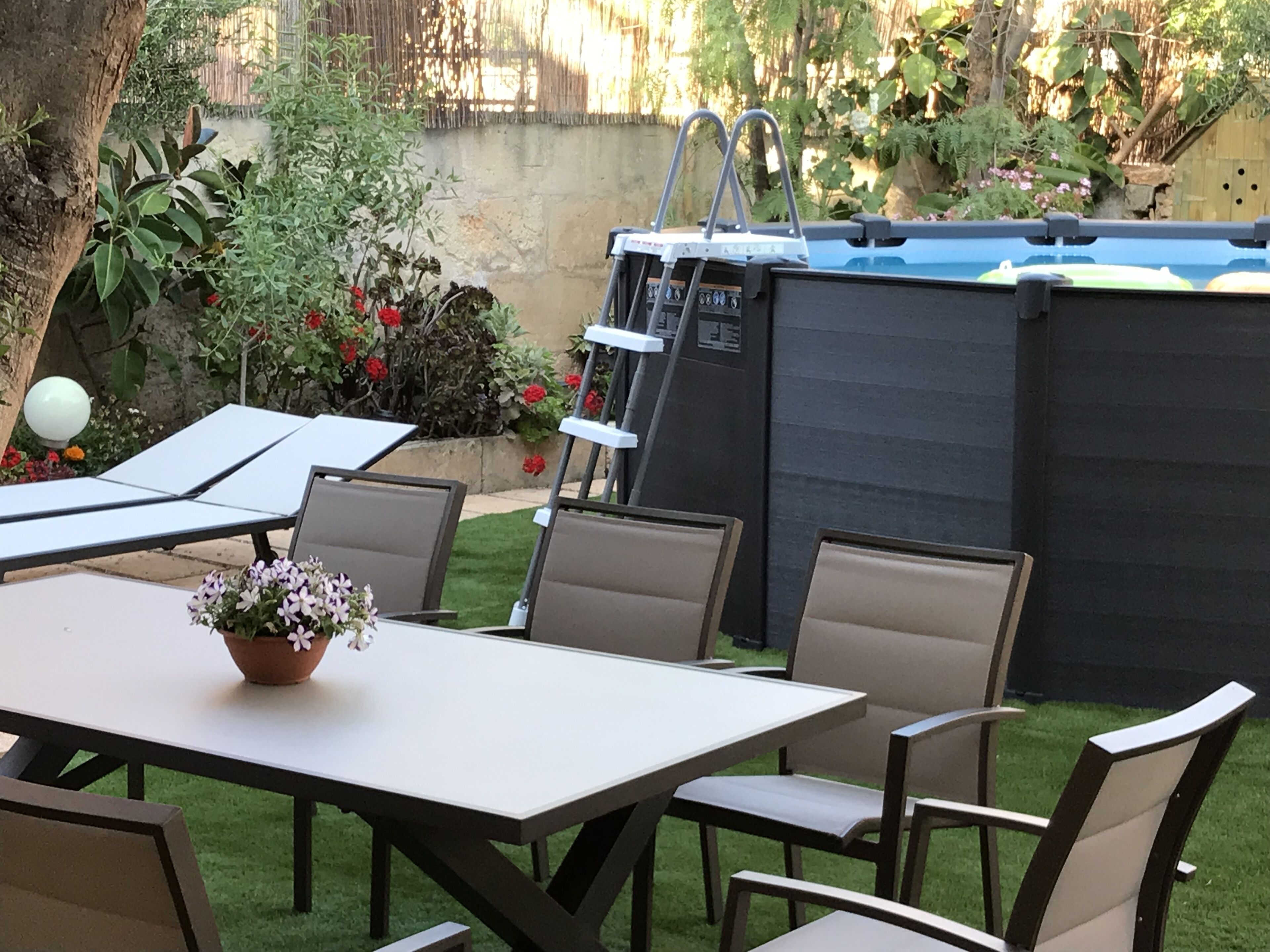 A patio with a table and chairs, a ladder, and a black storage unit.