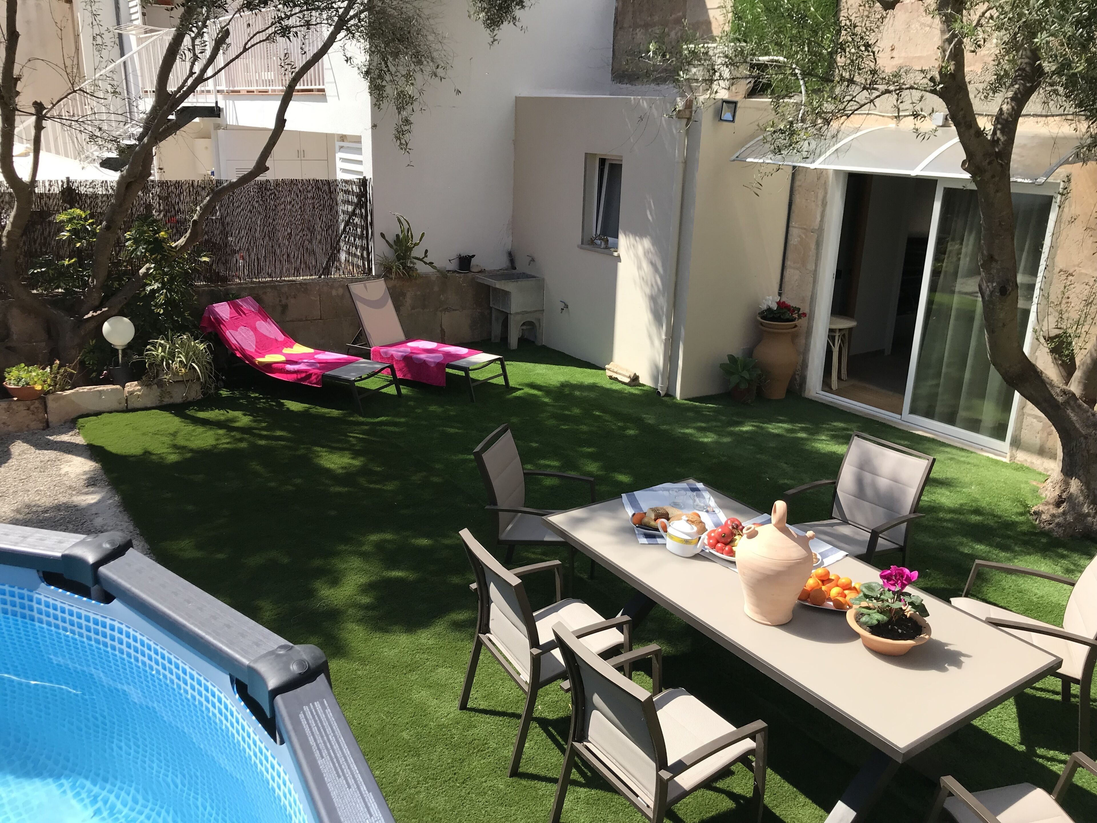 A backyard with a swimming pool, a dining table with chairs, and a seating area with lounge chairs.
