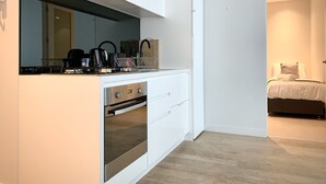 Una cocina moderna con armarios blancos, horno empotrado y campana extractora de acero inoxidable.