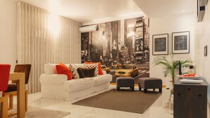 A modern living room with a white sofa, red and brown chairs, a coffee table, and a cityscape mural on the wall. - Porto RiverView Flat (Vila Nova de Gaia)